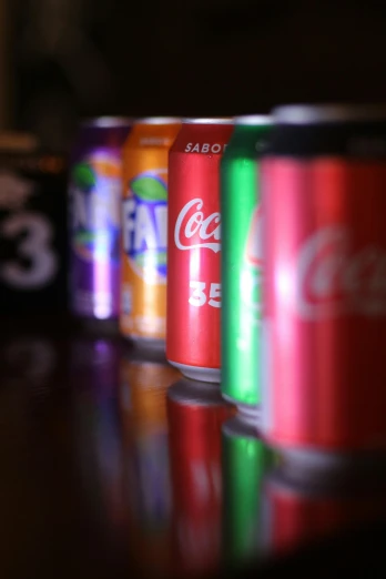 a row of soda cans sitting on top of a table, a picture, by Matt Cavotta, with a black background, alabama, the cool colors, cane