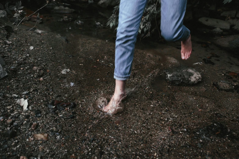 a person that is standing in the dirt, wet feet in water, running freely, wearing jeans, instagram post