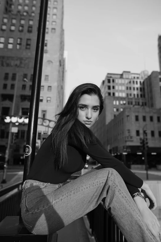 a black and white photo of a woman sitting on a ledge, a black and white photo, trending on pexels, realism, dua lipa, in a square, portrait sophie mudd, location [ chicago ( alley ) ]