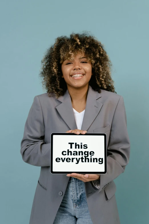 a woman holding a sign that says this change everything, an album cover, trending on pexels, sustainability, profile pic, diversity, thumbnail