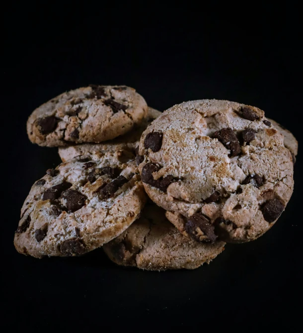 a pile of chocolate chip cookies on a black background, by Andries Stock, pexels, front view dramatic, 15081959 21121991 01012000 4k, high-angle, crumbling