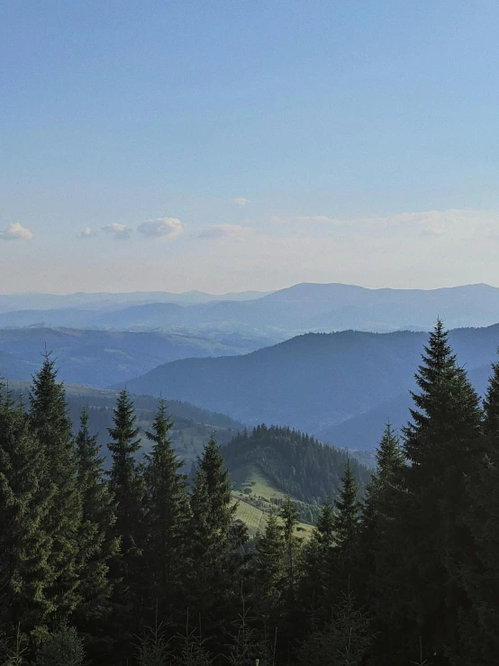 a man riding a snowboard on top of a snow covered slope, by Adam Szentpétery, pexels contest winner, forest fires in the distance, panorama distant view, late summer evening, spruce trees on the sides