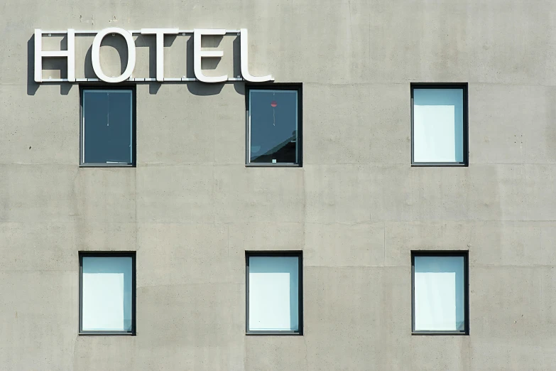 a hotel sign on the side of a building, inspired by Leandro Erlich, pexels contest winner, angular minimalism, thumbnail, big window, grey