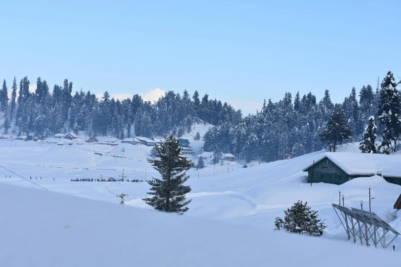 a man riding skis down a snow covered slope, by Muggur, pexels contest winner, hurufiyya, huts, evergreen valley, hill with trees, blue