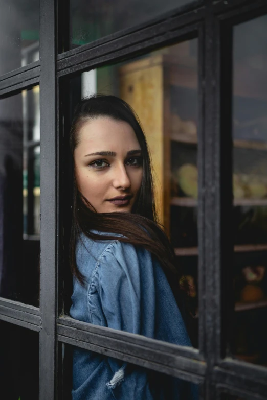 a woman is looking out of a window, pexels contest winner, photorealism, dilraba dilmurat, exiting store, headshot profile picture, in doors