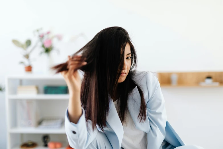 a woman sitting on a bed combing her hair, trending on pexels, hurufiyya, manuka, long thin black hair, wearing lab coat and a blouse, scratches on photo