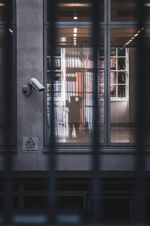 a security camera sitting on the side of a building, by Tobias Stimmer, pexels contest winner, modernism, the woman is behind bars, inside a library, man walking through city, view from behind mirror