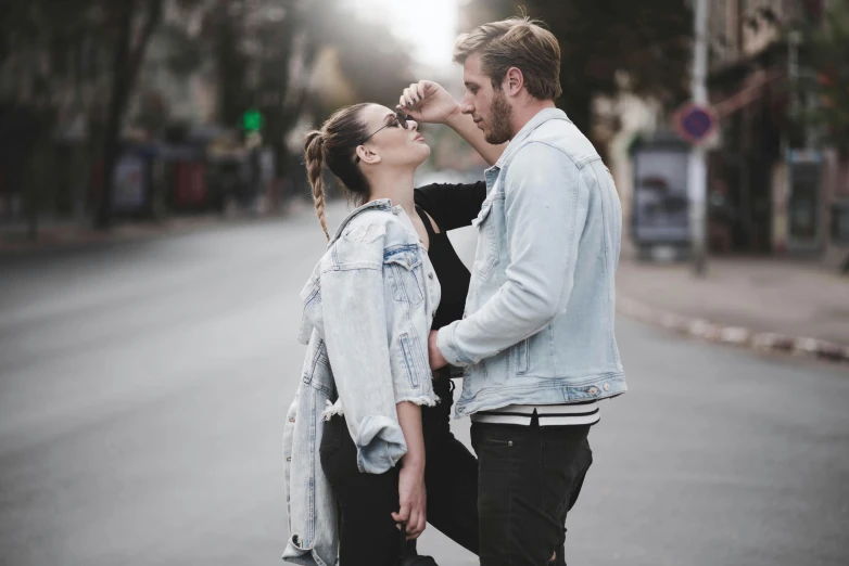 a man and woman standing next to each other on a street, trending on pexels, happening, jean jacket, beautiful girl, making out, sassy pose