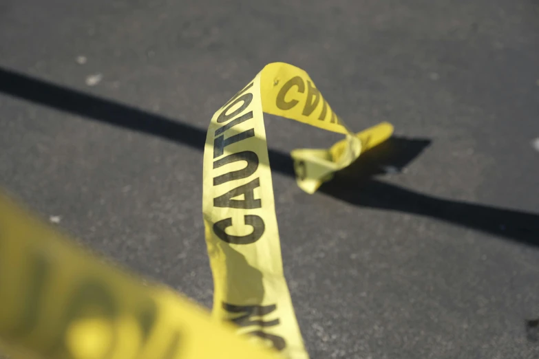 a close up of a yellow caution tape, gunfire, ap news photograph, thumbnail, modeled