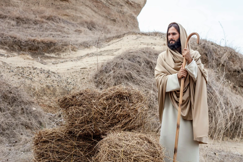 a man standing next to a pile of hay, inspired by Moses van Uyttenbroeck, unsplash, renaissance, dressed like jesus christ, scene from live action movie, australian, 2 0 2 2 photo