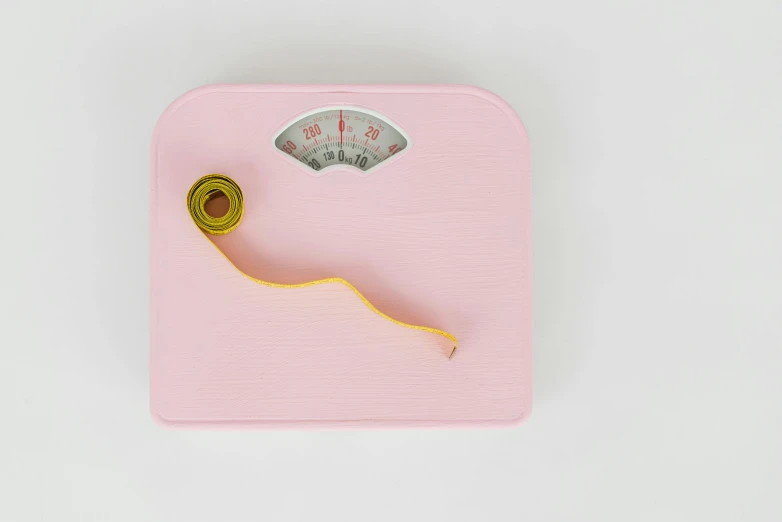 a scale with a measuring tape on it, by Emma Andijewska, trending on pexels, hyperrealism, pastel pink, worm, yellow, cottagecore!! fitness body
