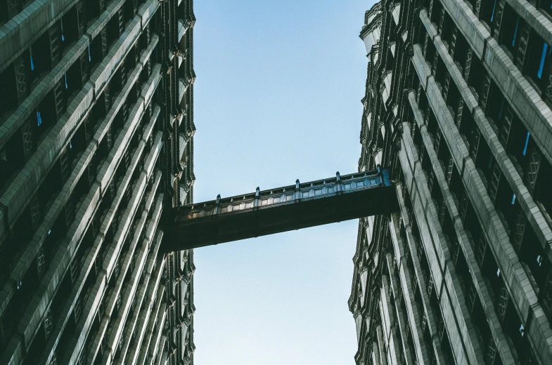 a couple of tall buildings next to each other, by Nick Fudge, pexels contest winner, brutalism, sky bridge, hanging upside down, cyberpunk elevated train, narrow passage