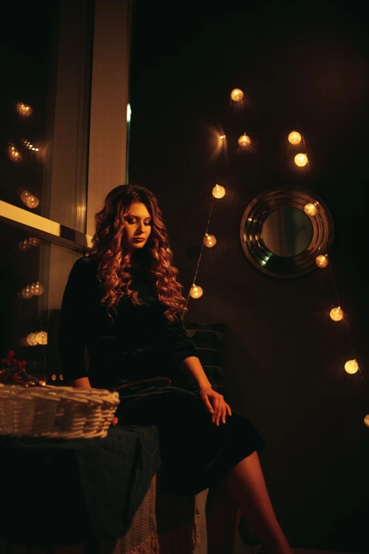 a woman sitting on a chair in front of a window, an album cover, by Julia Pishtar, pexels contest winner, fairy lights, long curly brown hair, reflecting light in a nightclub, kramskoi 4 k