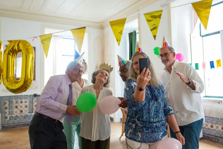 a group of people in a room with balloons, a photo, pexels contest winner, happening, elderly, accidentally taking a selfie, wearing a party hat, avatar image