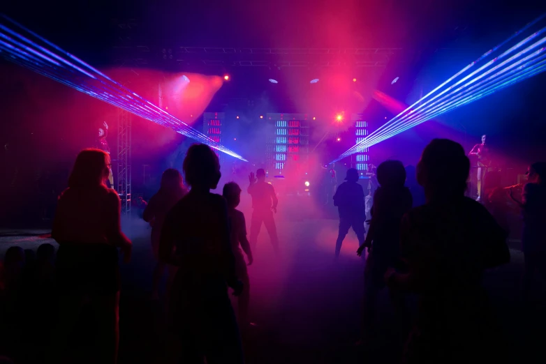 a group of people that are standing in the dark, clubs, pink and blue lighting, dancing lights, no - text no - logo