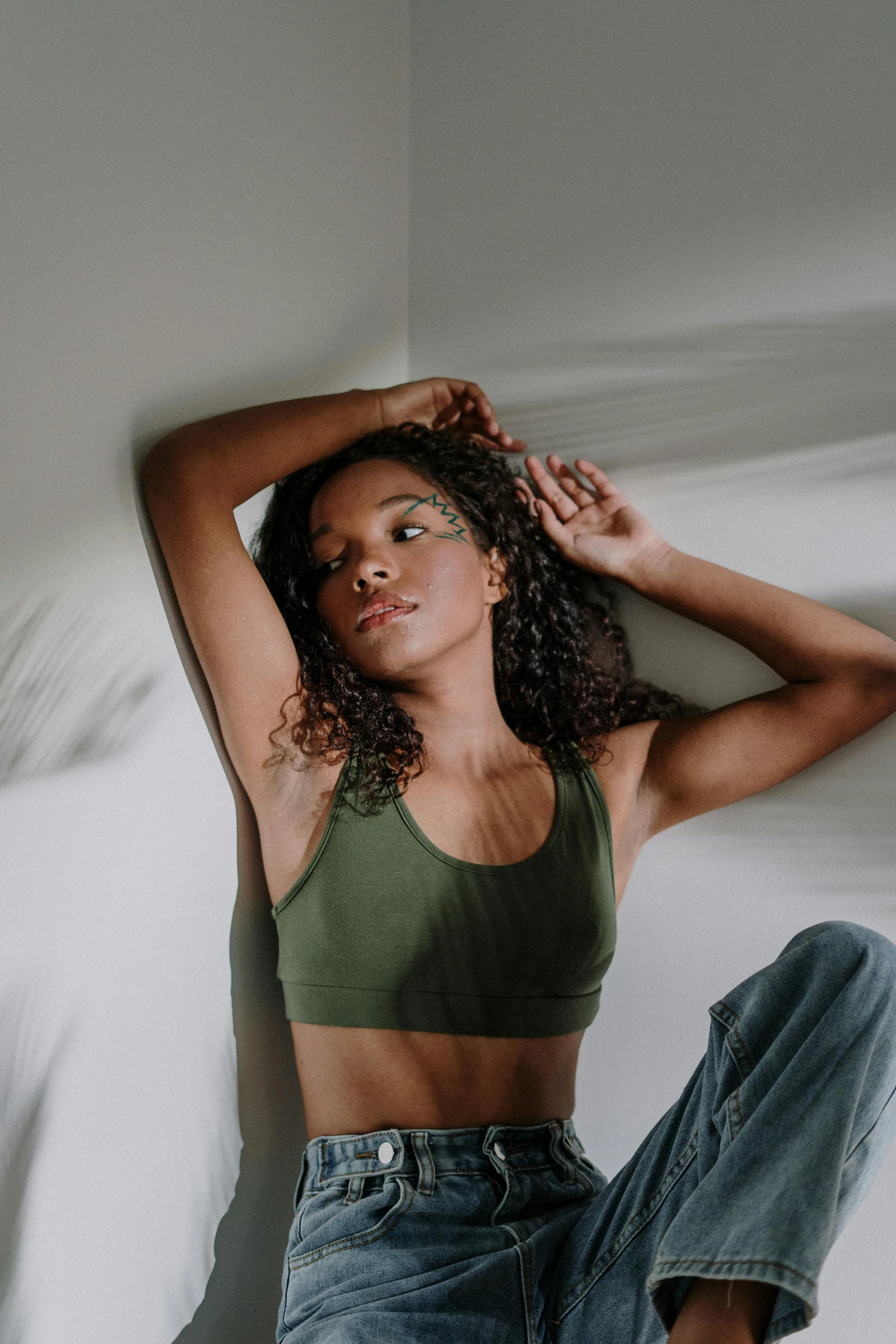 a beautiful young woman sitting on top of a bed, by Dulah Marie Evans, trending on pexels, renaissance, wearing a cropped tops, muted green, sports bra, mixed-race woman