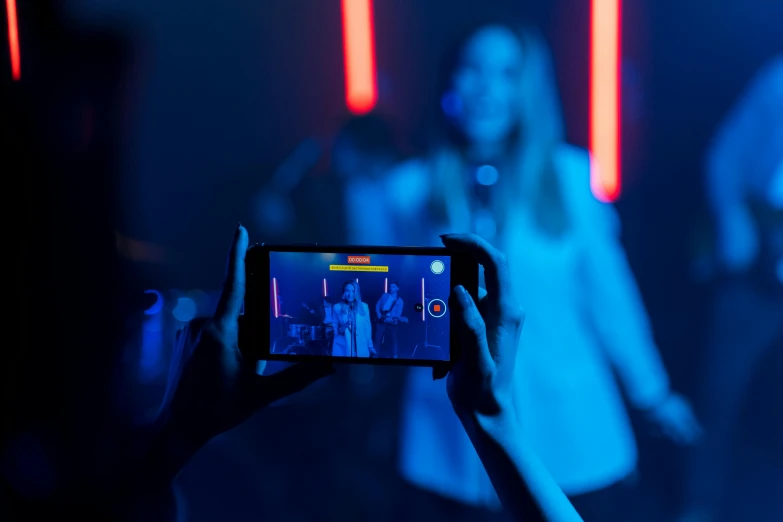 a person taking a picture with a cell phone, a hologram, pexels contest winner, happening, blue and orange lighting, performing a music video, models, avatar image