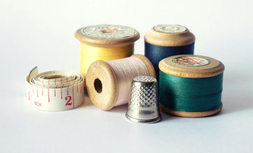 several spools of thread and a thimble, a picture, by Sylvia Wishart, unsplash, minimalism, 15081959 21121991 01012000 4k, museum photo, dials, analogue photo