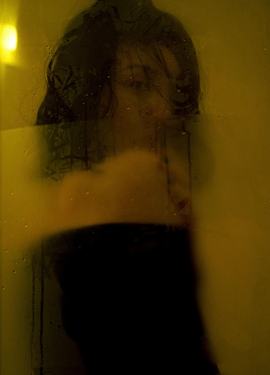 a woman in a black dress standing in front of a mirror, inspired by Elsa Bleda, under a shower, yellow tint, close - up photograph, person made out of glass