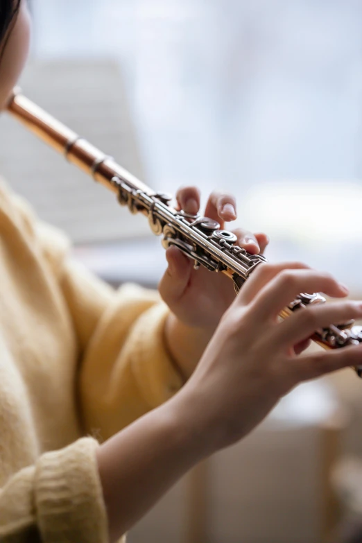 a woman in a yellow sweater playing a flute, shutterstock, blurred detail, mechanics, schools, 2019 trending photo