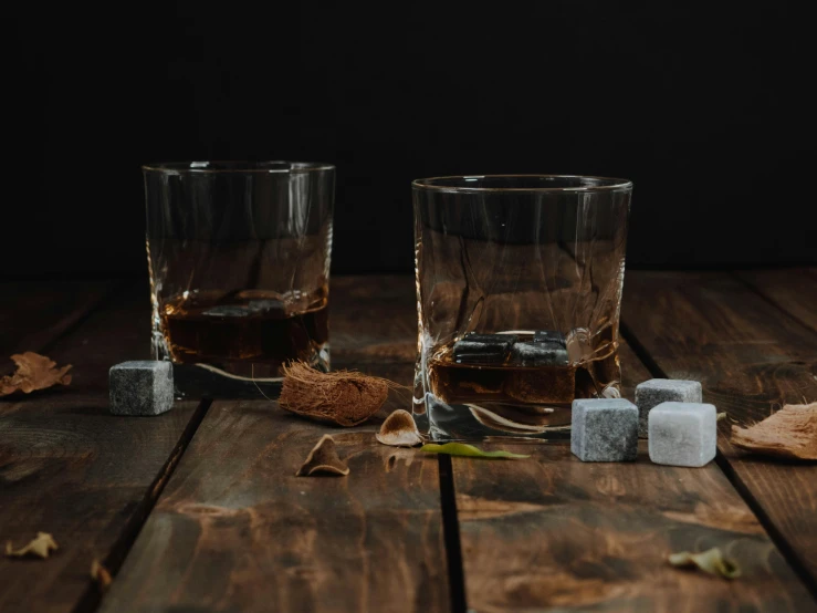 two glasses of whiskey with ice cubes on a wooden table, unsplash, square, with lots of dark grey rocks, game, various posed