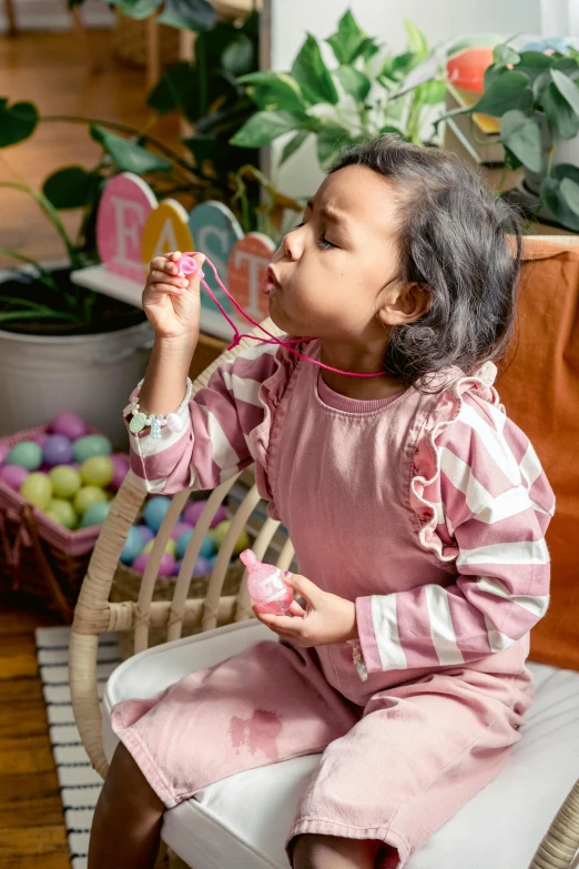 a little girl sitting on a chair blowing bubbles, pexels contest winner, holding easter eggs, putting on lipgloss, pink clothes, asian girl