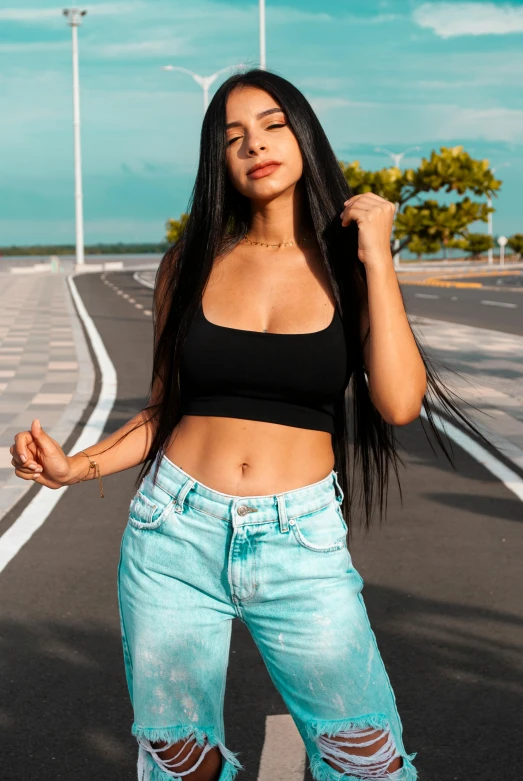 a woman standing on the side of a road, by Robbie Trevino, trending on pexels, hurufiyya, wearing a cropped black tank top, sky blue straight hair, brazilan supermodel, jeans and t shirt