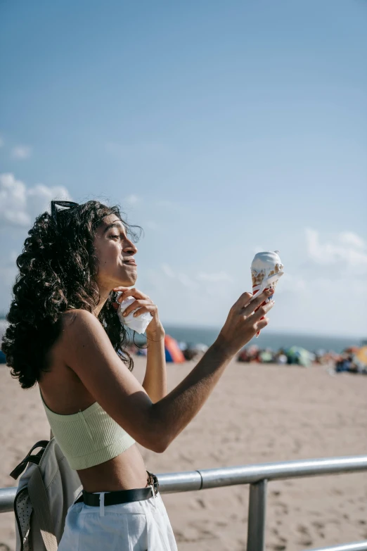 a woman eating ice cream on the beach, by Niko Henrichon, pexels contest winner, happening, carrying a bottle of perfume, new jersey, blocking the sun, curls