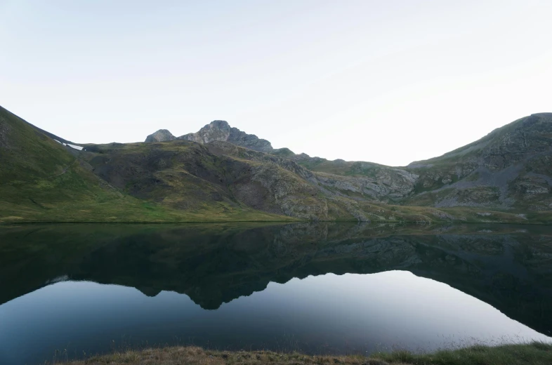 a body of water with mountains in the background, by Werner Andermatt, unsplash, les nabis, late summer evening, big mirrors, grey, rinko kawauchi