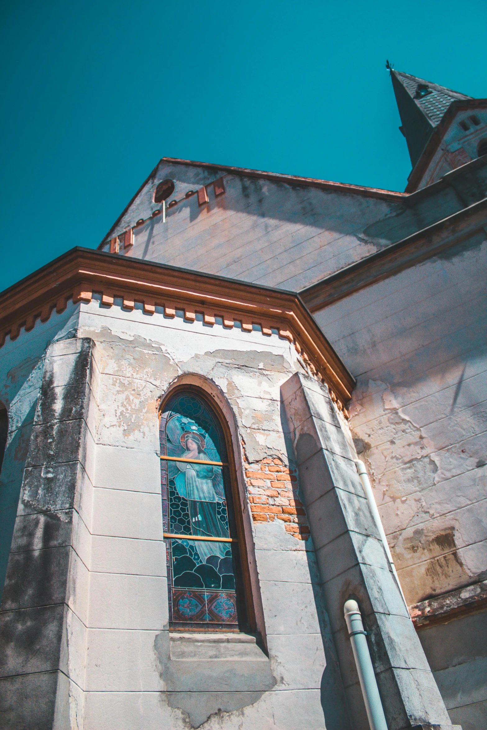 an old church with a stained glass window, a picture, unsplash contest winner, romanesque, blue sky, patina, street corner, up-angle view