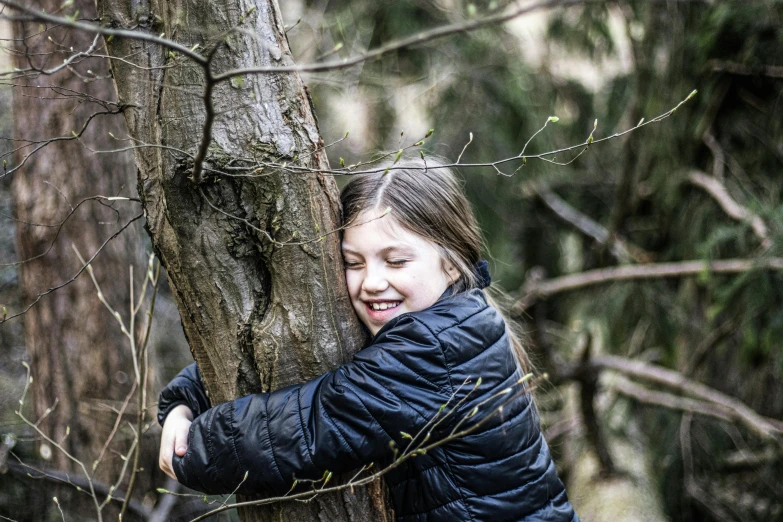 a young girl hugging a tree in the woods, inspired by Andy Goldsworthy, unsplash, greta thunberg smiling, hidden area, playing, press shot