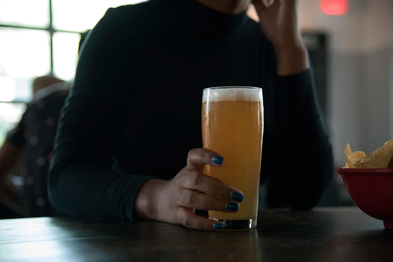 a person sitting at a table with a glass of beer, by Carey Morris, pexels, photo of a black woman, from the elbow, 15081959 21121991 01012000 4k, hop cone juice