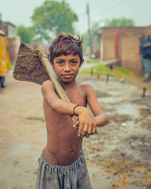 a young boy holding a shovel on a dirt road, an album cover, inspired by Steve McCurry, pexels contest winner, streets of calcutta, very buff, thumbnail, lgbtq