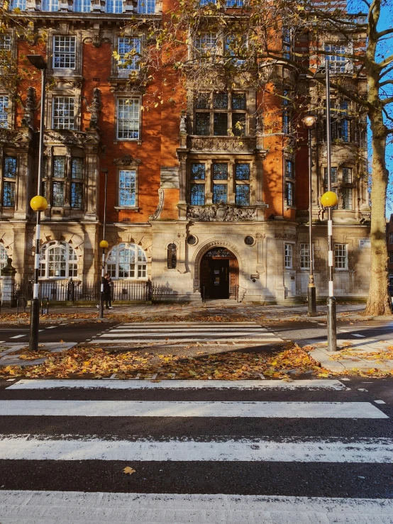 a building with a crosswalk in front of it, inspired by Sydney Prior Hall, unsplash, heidelberg school, covered in fallen leaves, london, low quality photo, artsationhq