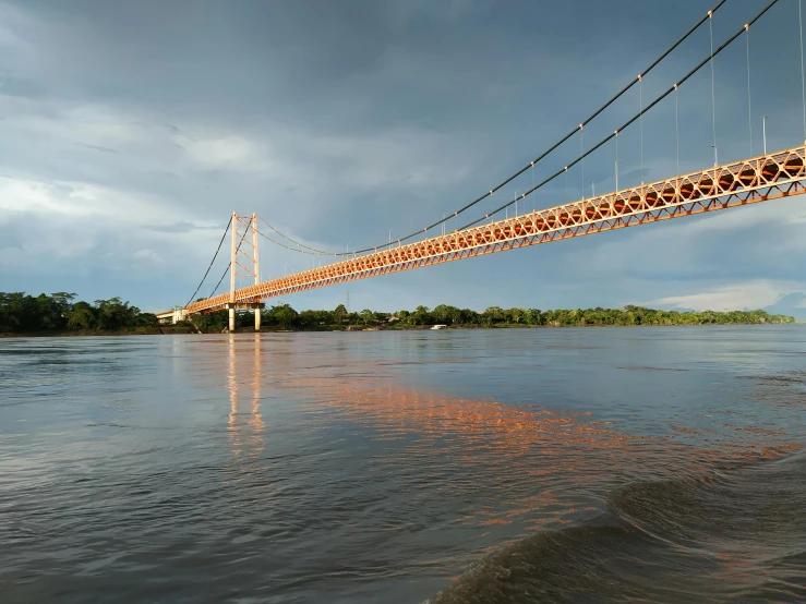 a bridge over a body of water under a cloudy sky, a digital rendering, inspired by Christo, unsplash contest winner, sōsaku hanga, calcutta, 1 glowing bridge crossing river, samburu, thumbnail