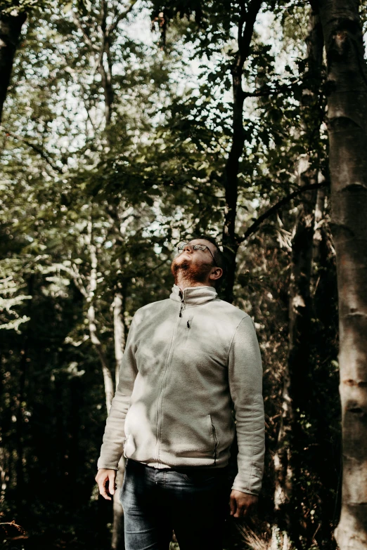 a man standing in the woods with a frisbee, unsplash, renaissance, wearing a turtleneck and jacket, looking upward, promo image, trees growing on its body