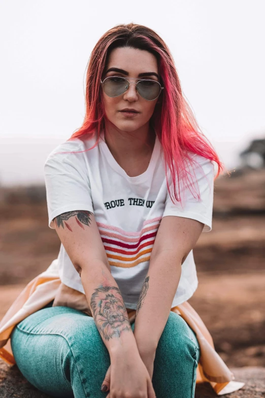 a woman with pink hair sitting on a rock, trending on pexels, t-shirt, aviators, gradient white to red, don't trip