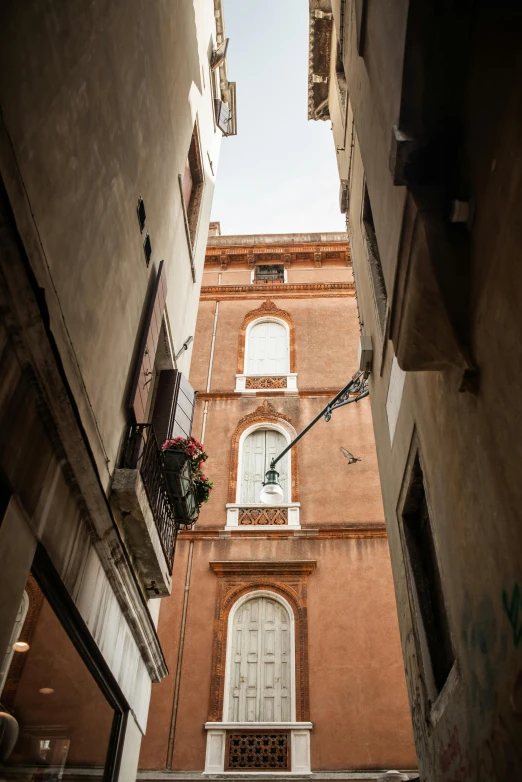 a narrow alley with a clock tower in the background, by Riad Beyrouti, renaissance, seen from a distance, red building, camera angle from below, square