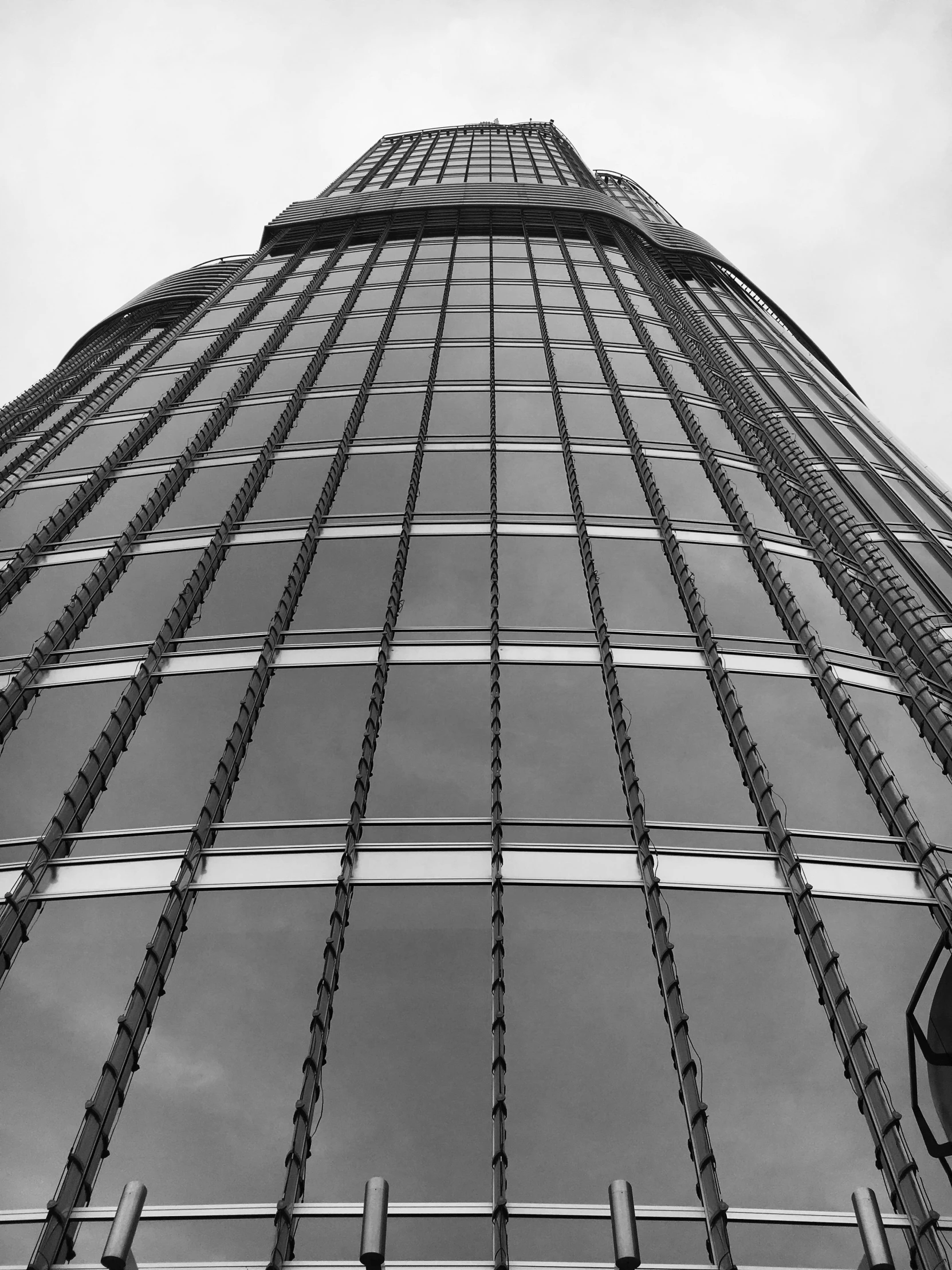 a black and white photo of a tall building, by Adam Rex, lots of glass details, hanging cables, worm\'s eye view, taken on an iphone