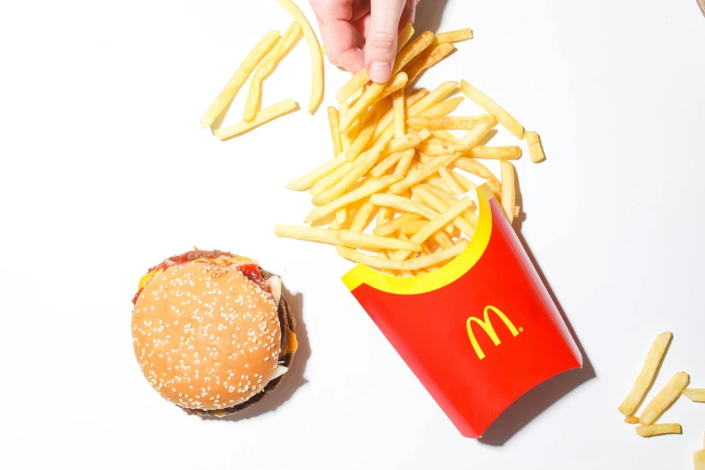 a person reaching for french fries next to a hamburger, an album cover, by Julia Pishtar, unsplash, mcdonalds restaurant, set against a white background, 15081959 21121991 01012000 4k, flatlay