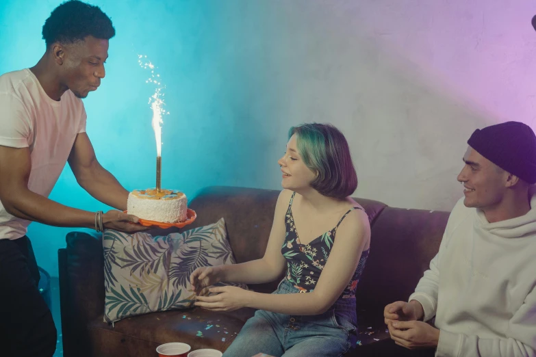 a group of people sitting around a table with a cake, inspired by Elsa Bleda, pexels contest winner, bisexual lighting, holding a torch, teenage girl, background image