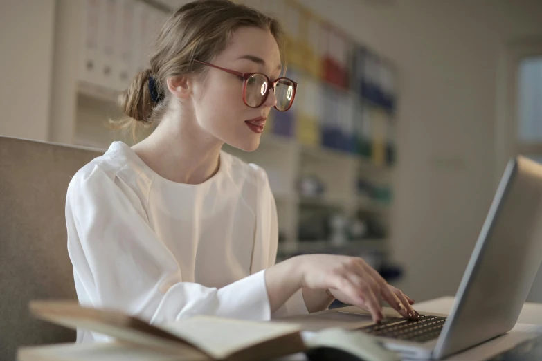 a woman sitting in front of a laptop computer, trending on pexels, library nerd glasses, lachlan bailey, academic clothing, thumbnail