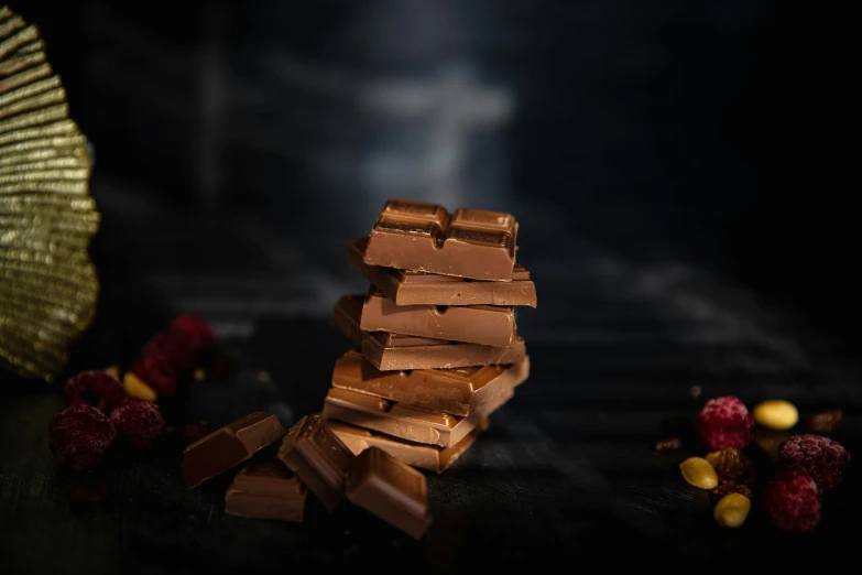 a pile of chocolate sitting on top of a table, dark surroundings, detailed product image, lit from the side, gracked