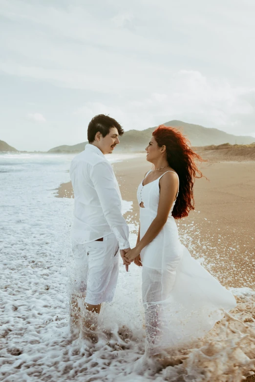 a man and woman standing next to each other on a beach, by Lucia Peka, pexels contest winner, renaissance, wearing white cloths, waves and splashes, gif, pr shoot