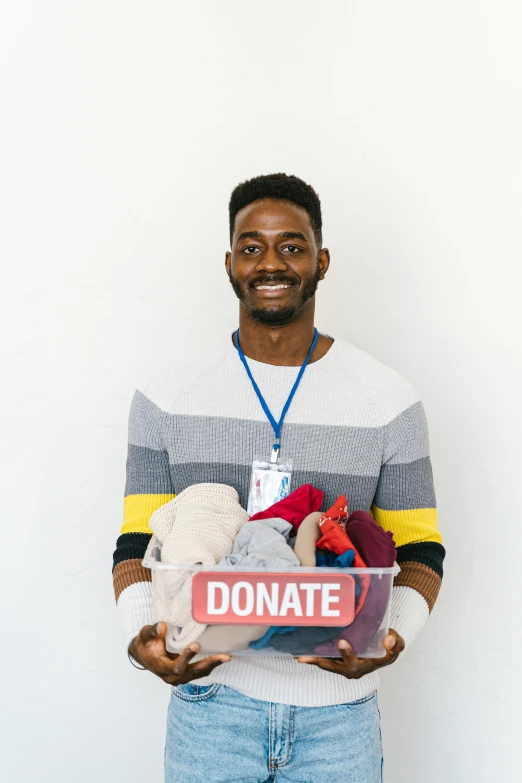 a man holding a donation sign and stuffed animals, a colorized photo, pexels contest winner, dark skinned, handsome male, a person standing in front of a, helpful