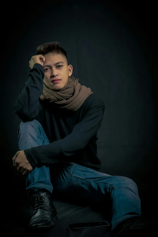 a man sitting on the ground wearing a scarf, a character portrait, inspired by Nabil Kanso, pexels contest winner, studio!! portrait lighting, like andy lau, wearing jeans and a black hoodie, avatar image