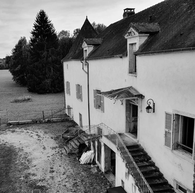 a black and white photo of an old house, a black and white photo, by Cedric Peyravernay, pexels, barbizon school, drone photograpghy, in the yard, beside the river, ground view