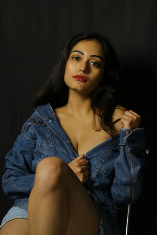 a beautiful young woman sitting on top of a chair, by Matthias Stom, reddit, jean jacket, provocative indian, close up portrait photo, low quality photograph