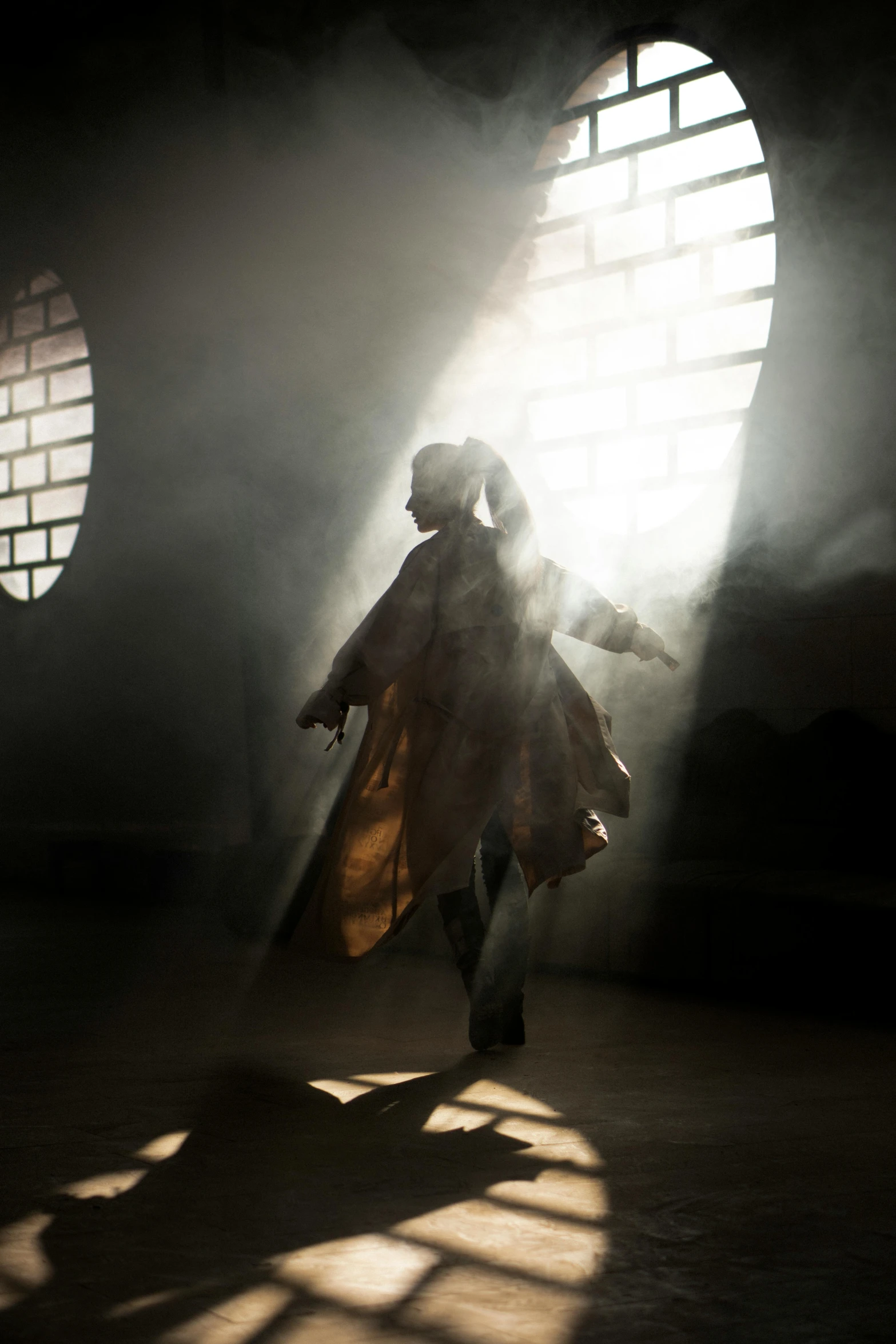 a man that is standing in front of a window, pexels contest winner, light and space, a young woman as genghis khan, whirling, ( ( theatrical ) ), studio dramatic light