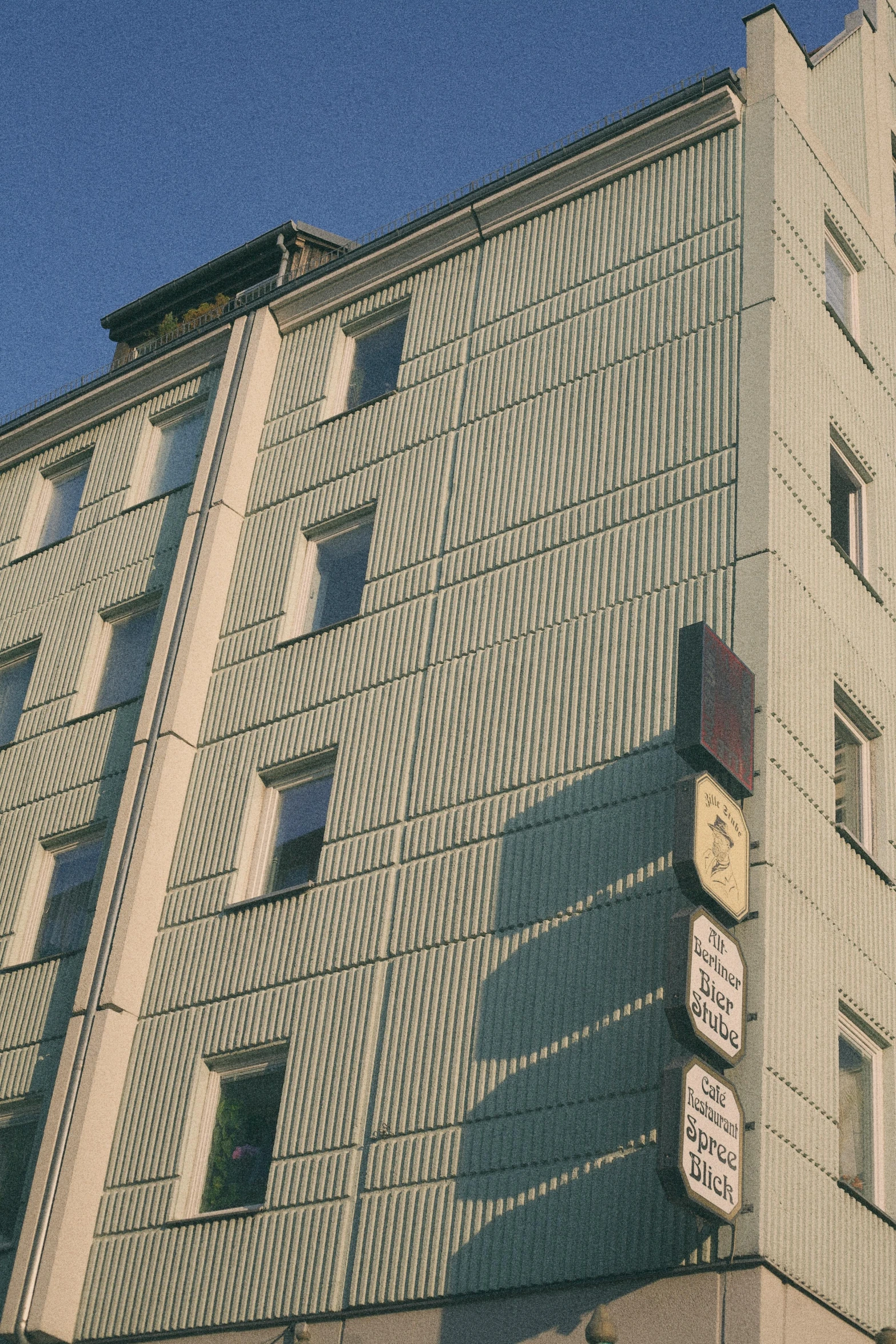 a tall building with a clock on the side of it, inspired by Albert Paris Gütersloh, flickr, hotel room, post - soviet courtyard, warm shading, view from ground level